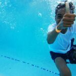 under water photography of boy showing thumb